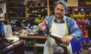 Man with pliers in his hand working on bromn men's shoes