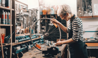 a lady working on a bike wheel on a wooden desk at a bike repair shop