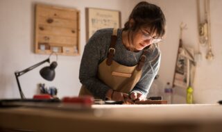 A female Carpenter working at a table wearing glasses.