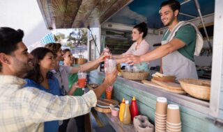 Waitress and waiter giving juice to customer at counter