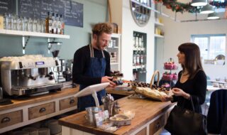 Female Customer Paying In Coffee Shop