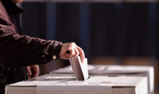 A person placing their ballot into a Voting Box