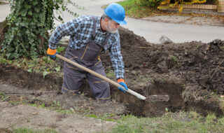 Construction worker digging trench using shovel
