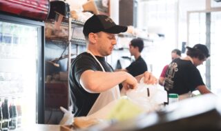 Male worker behind a counter preparing a bag of bagels