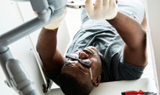 Male working on plumbing underneath the sink of a home