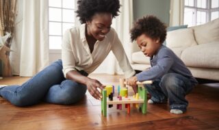 Mother And Young Son Playing With Wooden Toy At Home