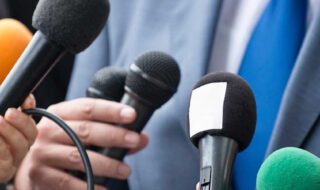 multiply microphones being helpd up to a non discriptive person that is unseen