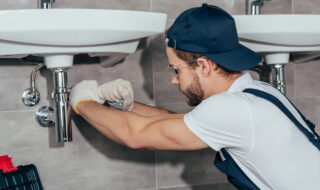 close-up view of young professional plumber fixing sink in bathroom